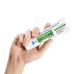 A hand holds a tube of Globe Hemorrhoid Symptom Treatment Cream (1.8 oz), for pain relief with aloe, featuring white, green, and blue labeling by Globe, against a plain white background.
