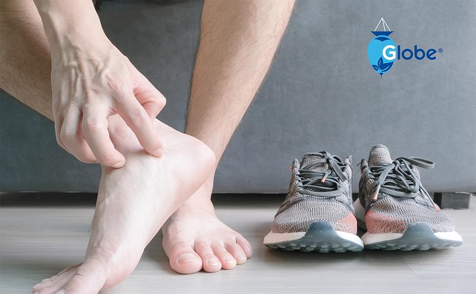 A person sitting on the floor scratches their bare heel, suggesting possible jock itch, with a pair of gray and pink running shoes nearby. Globe Clotrimazole Antifungal Cream 1% (4 oz) is displayed in the top right corner.