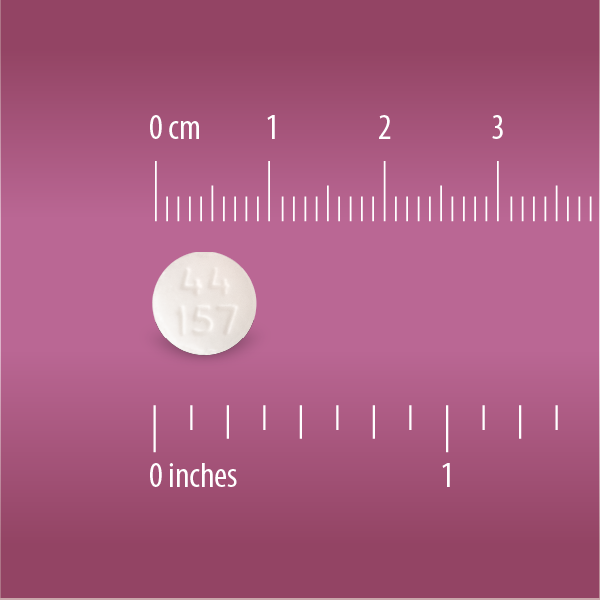 A small round white uncoated Globe Aspirin 325mg tablet (NSAID pain reliever) is shown on a pink background next to rulers in centimeters and inches, highlighting its size; commonly used for pain and fever relief.