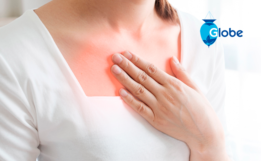 A person in a white shirt touches their upper chest, with a red area showing heartburn pain that Globe Chewable Mint Antacid Tablets can help relieve. The Globe logo is displayed in the top right corner.