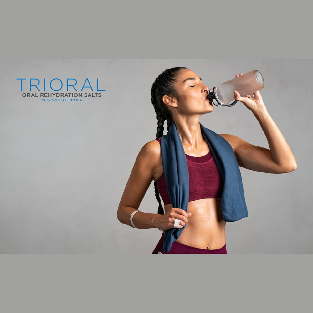 A fit woman in a sports bra and leggings with braids drinks TRIORAL Natural Lemon w/ Stevia Oral Rehydration Salts (WHO formula) from a water bottle after her workout, enjoying dehydration relief. “TRIORAL” appears on the left.