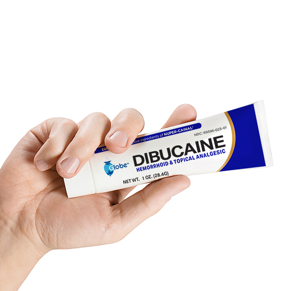 A hand holds a tube of Globe Dibucaine 1% Hemorrhoid Treatment Ointment, 1 oz, Rapid Numbing Relief for pain, itch, and burn, against a white background.