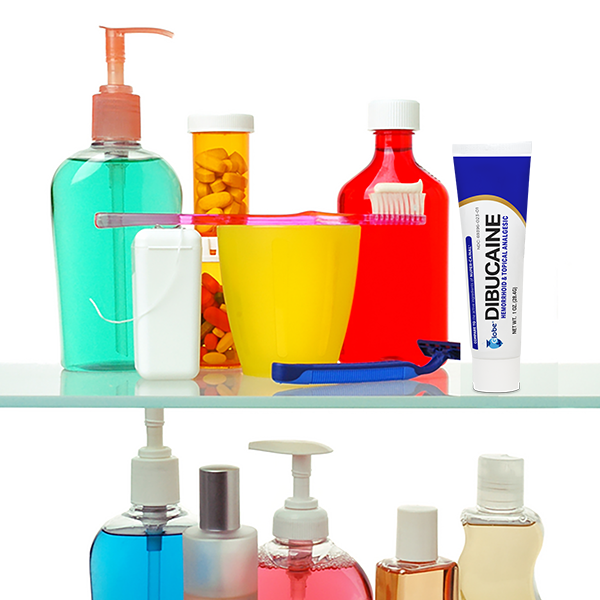 A bathroom shelf holds bottles of soap and mouthwash, a yellow cup with a pink toothbrush, a container of orange pills, Globe Dibucaine 1% Hemorrhoid Treatment Ointment for rapid relief, and assorted toiletry items.