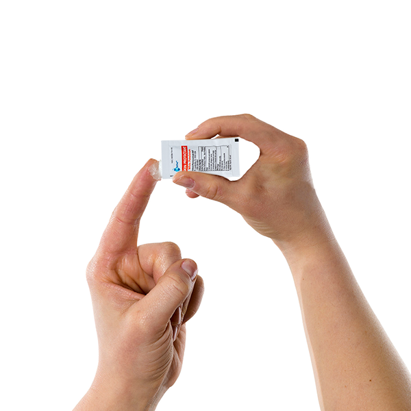 A person squeezes Globe White Petrolatum, a soothing petroleum jelly for dry or cracked skin, from a small 5g packet onto their finger against a plain white background.