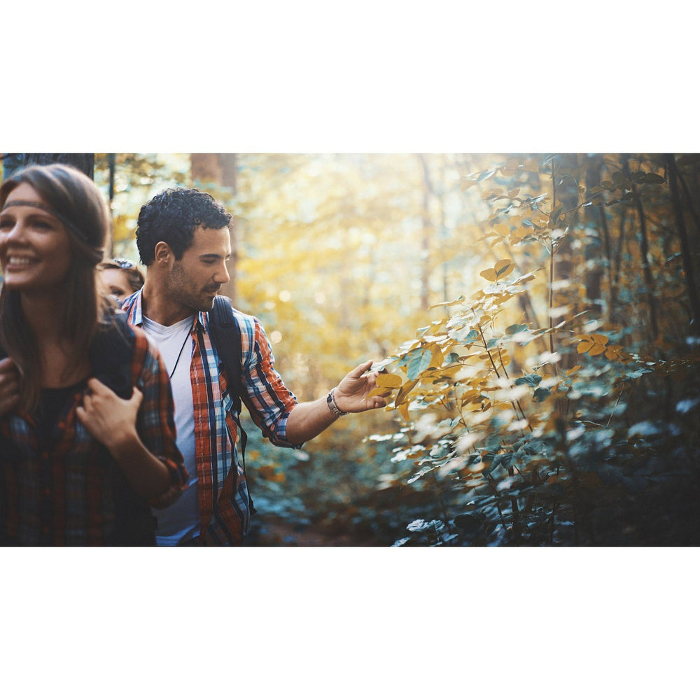 A man and woman explore a sunlit forest, ready with Rhuli Gel—an analgesic anti-itch treatment for fast relief from bug bites, poison ivy, and sunburn—so their hike stays comfortable and itch-free.